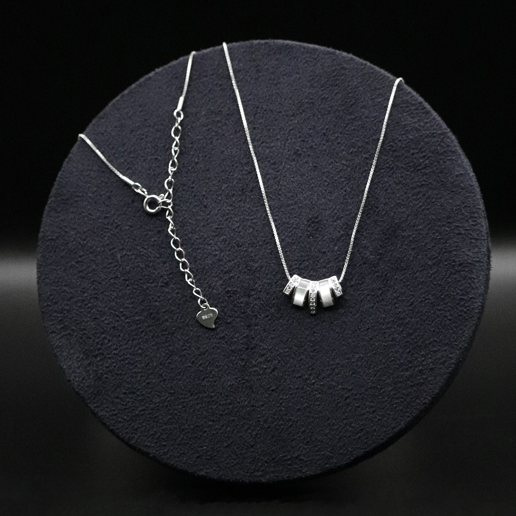 Two silver necklaces on a dark round surface