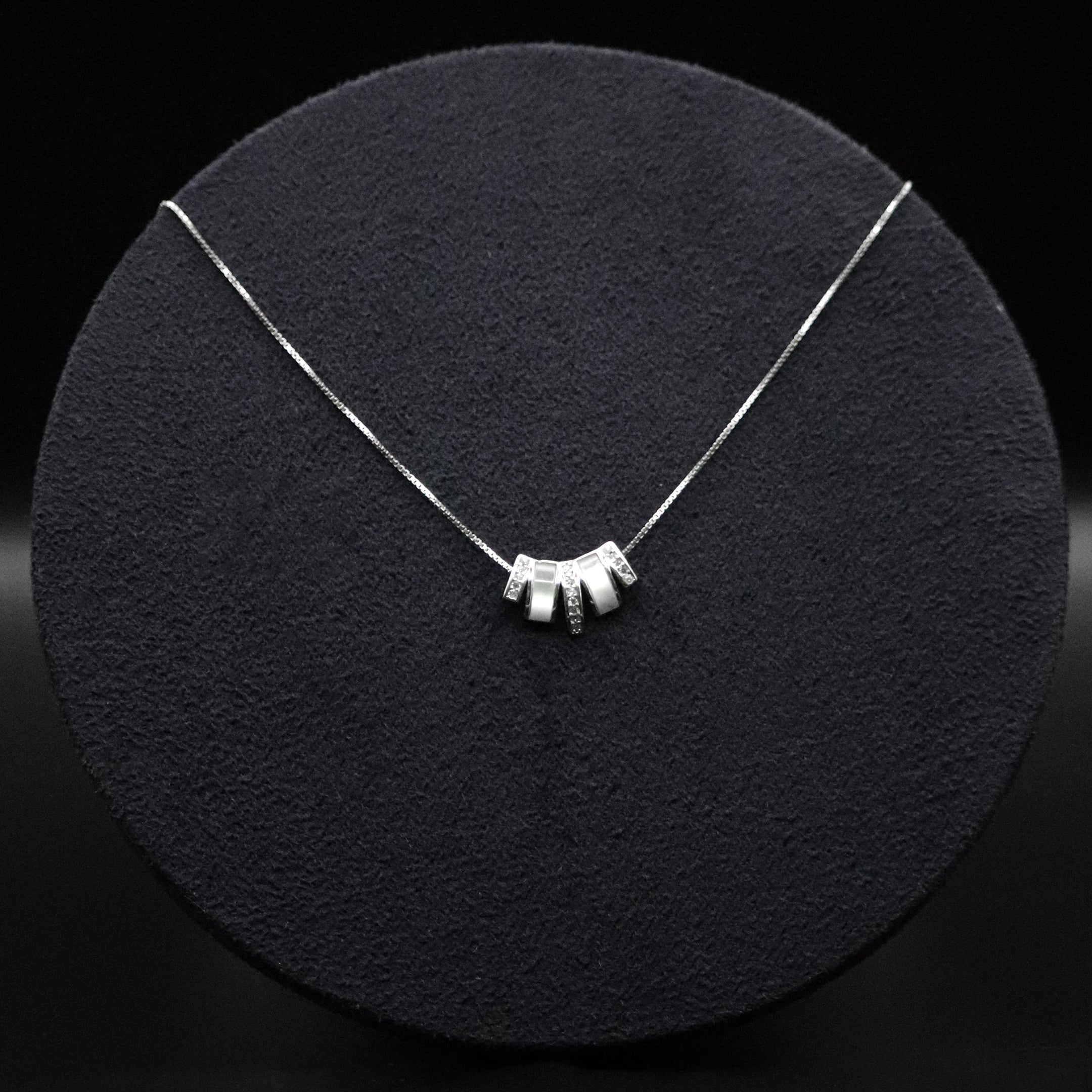 Silver necklace with a unique design on a black textured surface