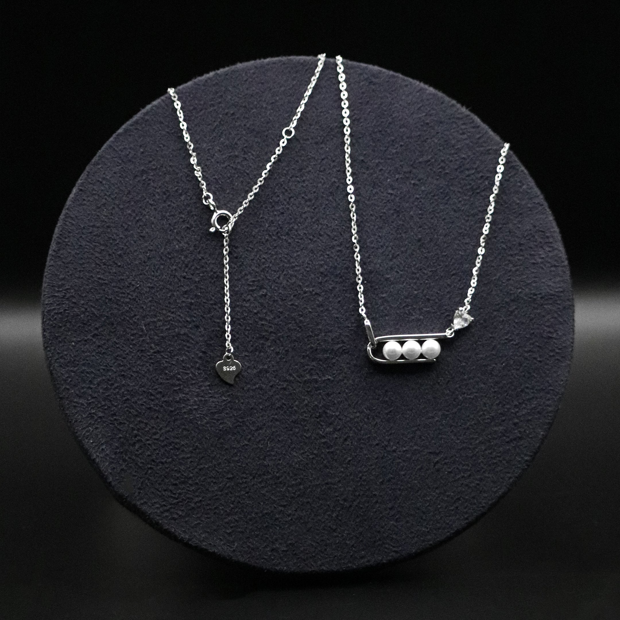 Two silver necklaces on a black textured surface