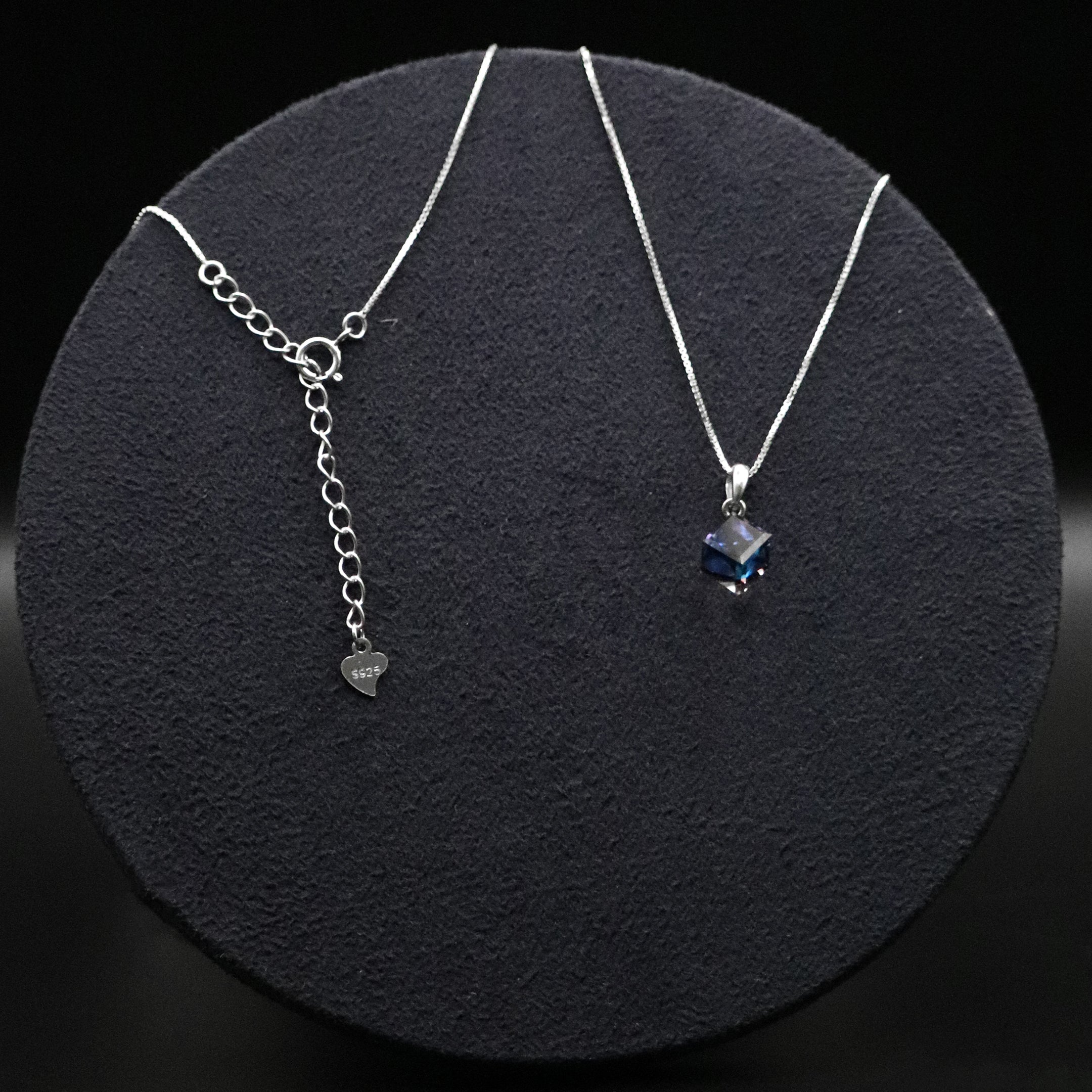 Two silver necklaces with gemstones on a dark textured surface