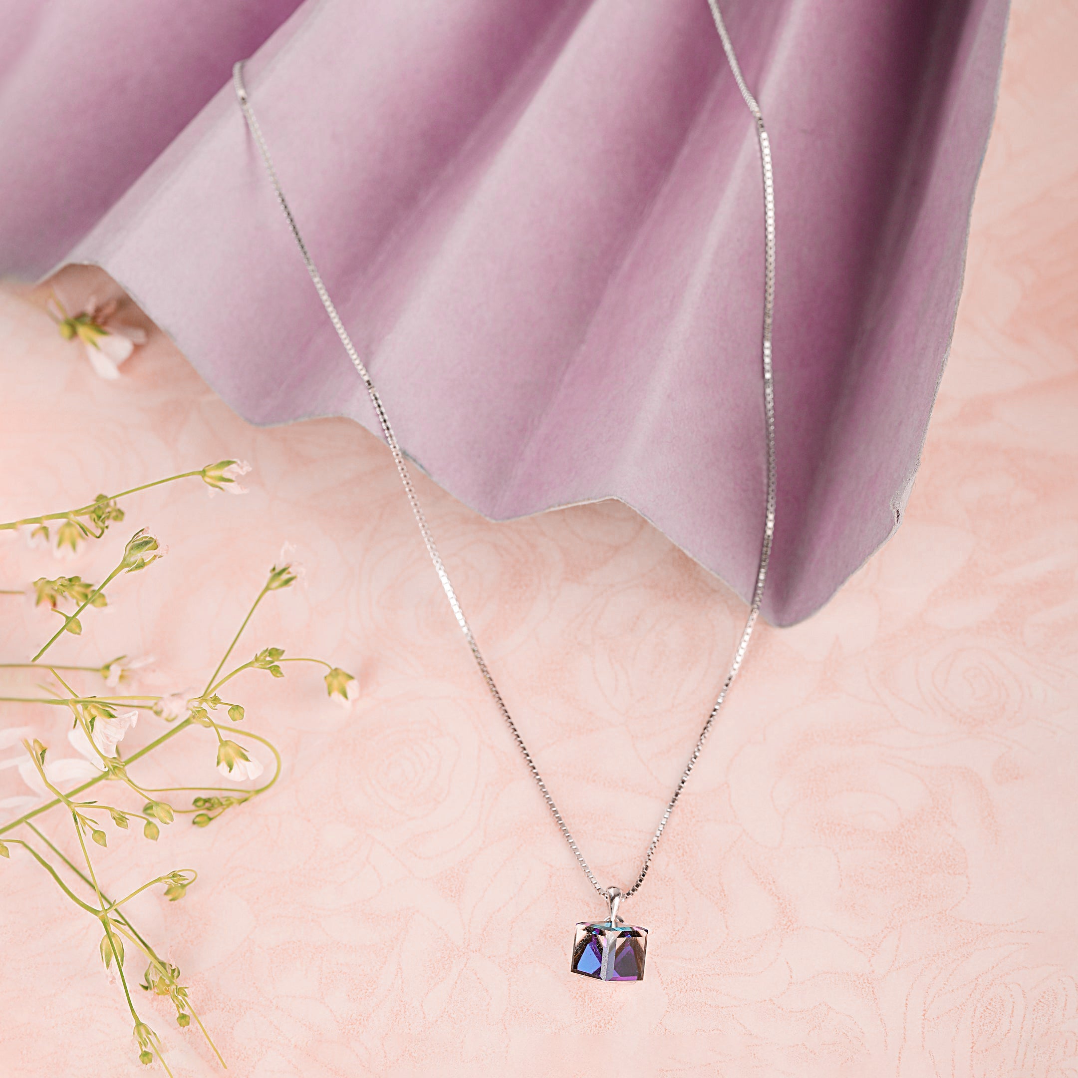 Necklace with a colorful pendant on a person's neck against a soft pink background