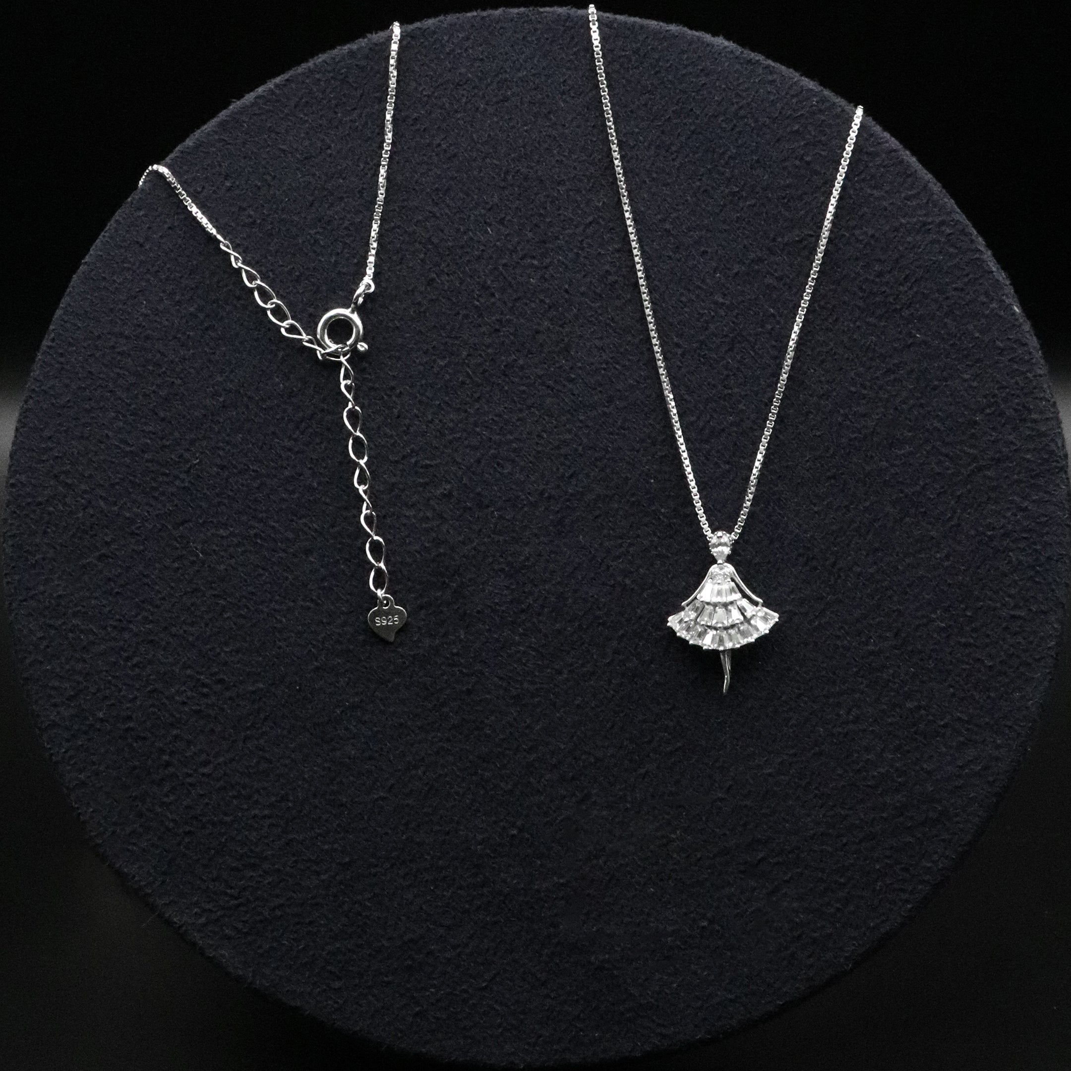Two silver necklaces on a black textured surface