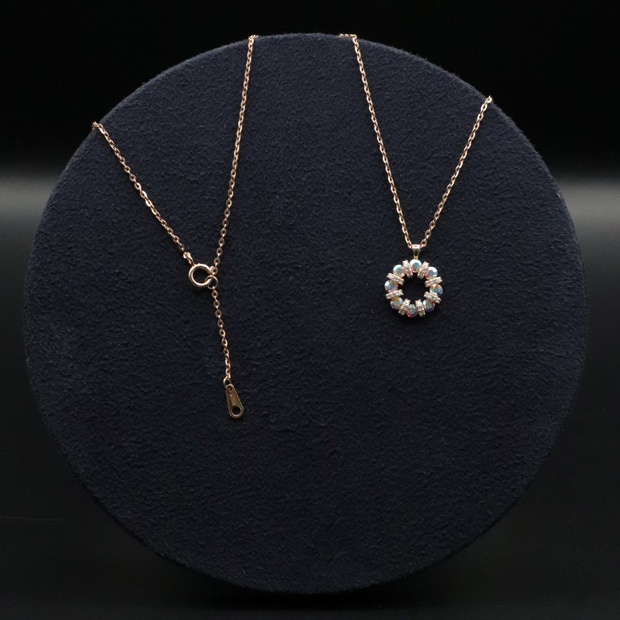 Gold necklace with a round pendant on a dark background