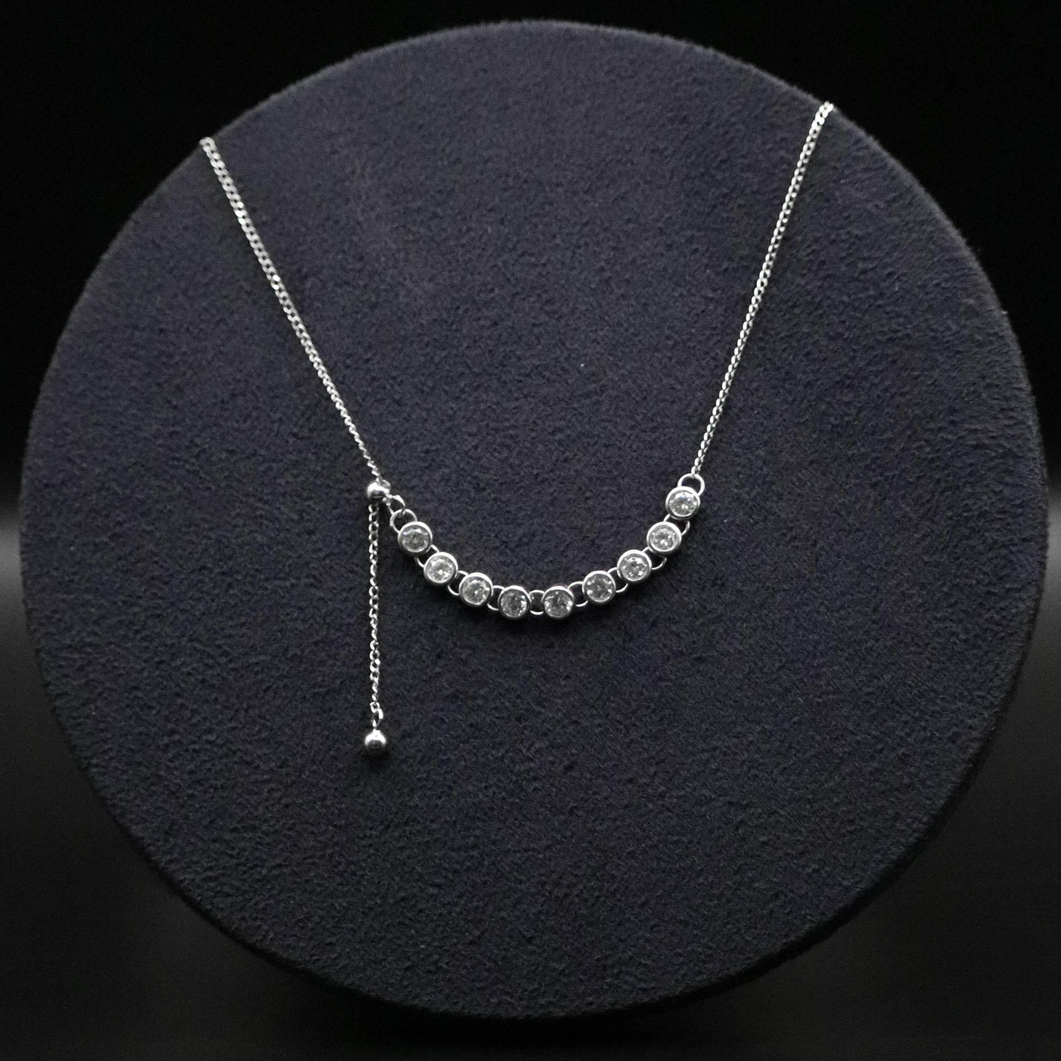 Silver necklace with small beads on a black circular stand