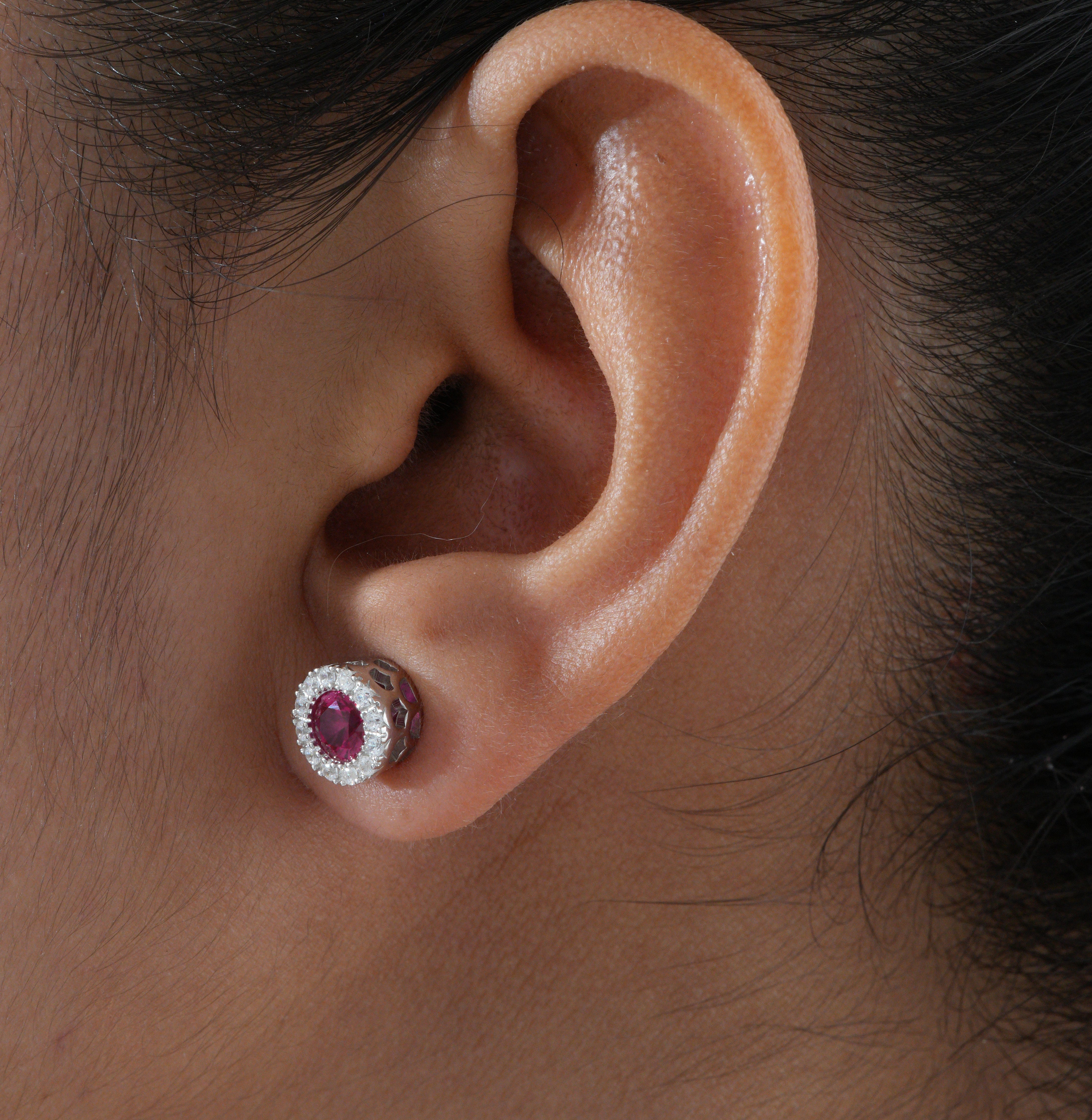 Close-up of an ear wearing a diamond and ruby earring.