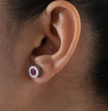 Close-up of an ear wearing a diamond and ruby earring.