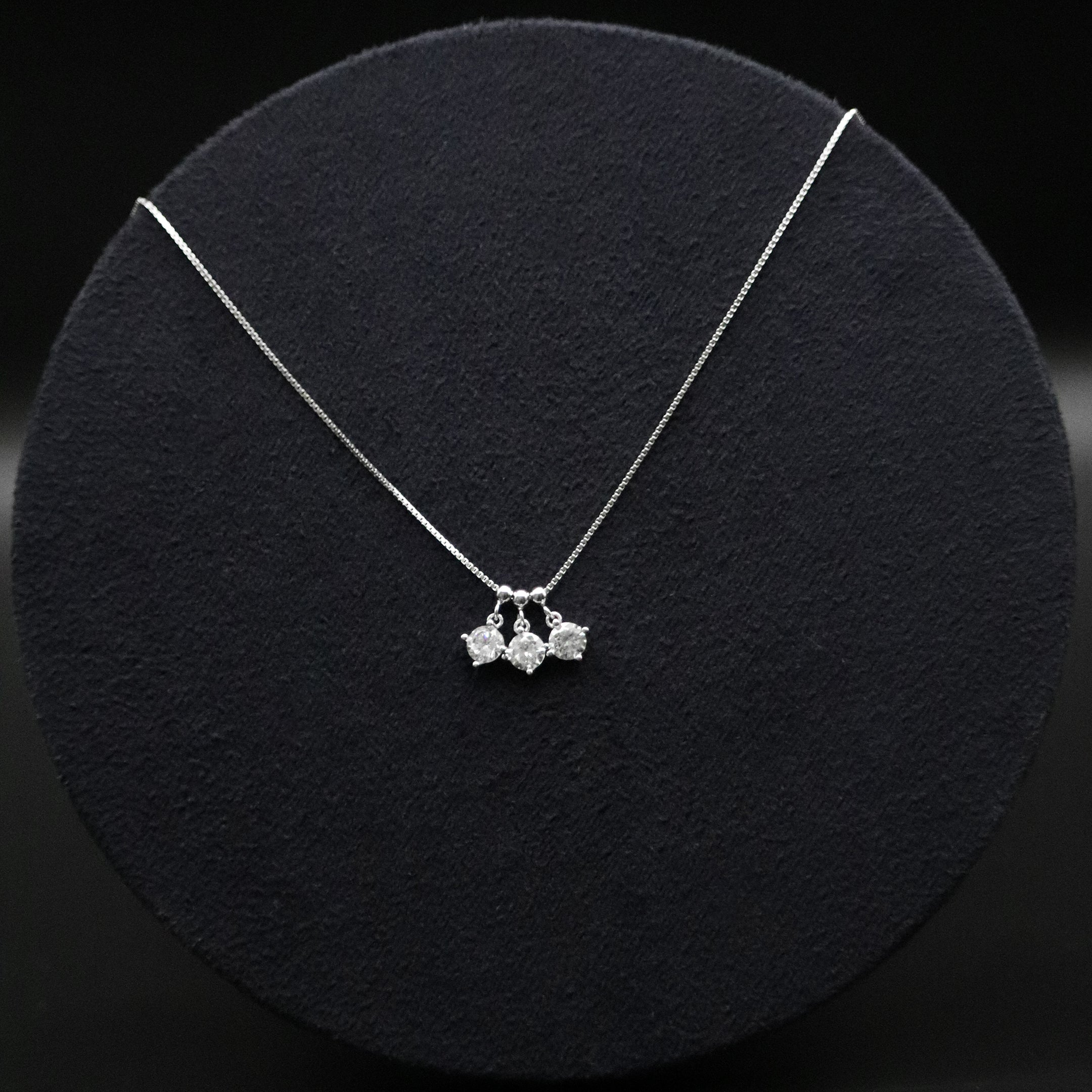 Silver necklace with three pendant drops on a black background