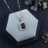 Silver necklace with a blue gemstone pendant on a blue cushion