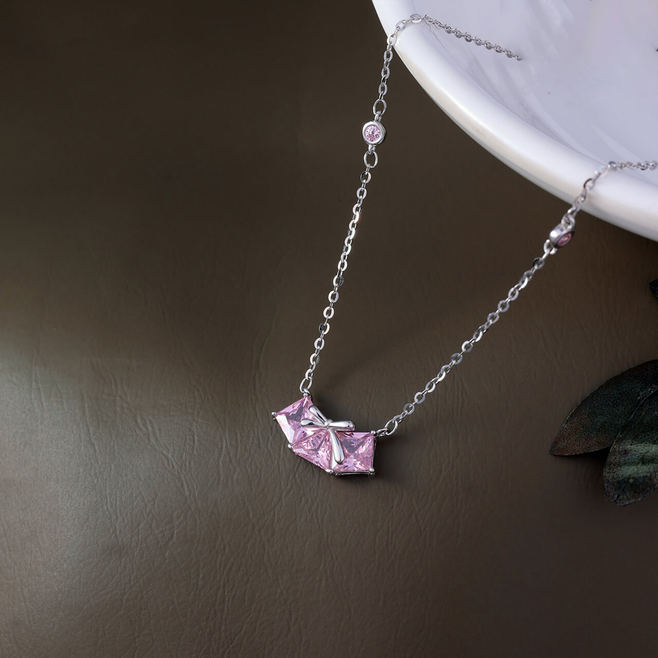 Necklace with a pink geometric pendant on a brown surface