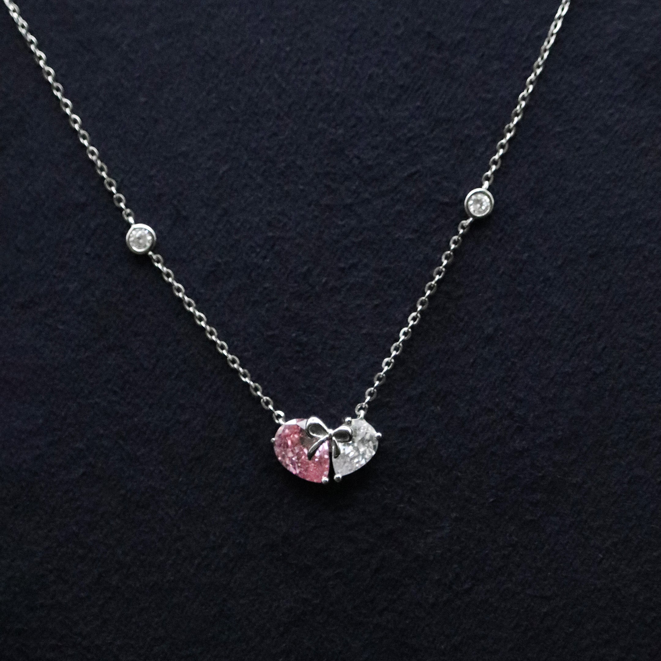 Necklace with heart and bow pendant on a dark background