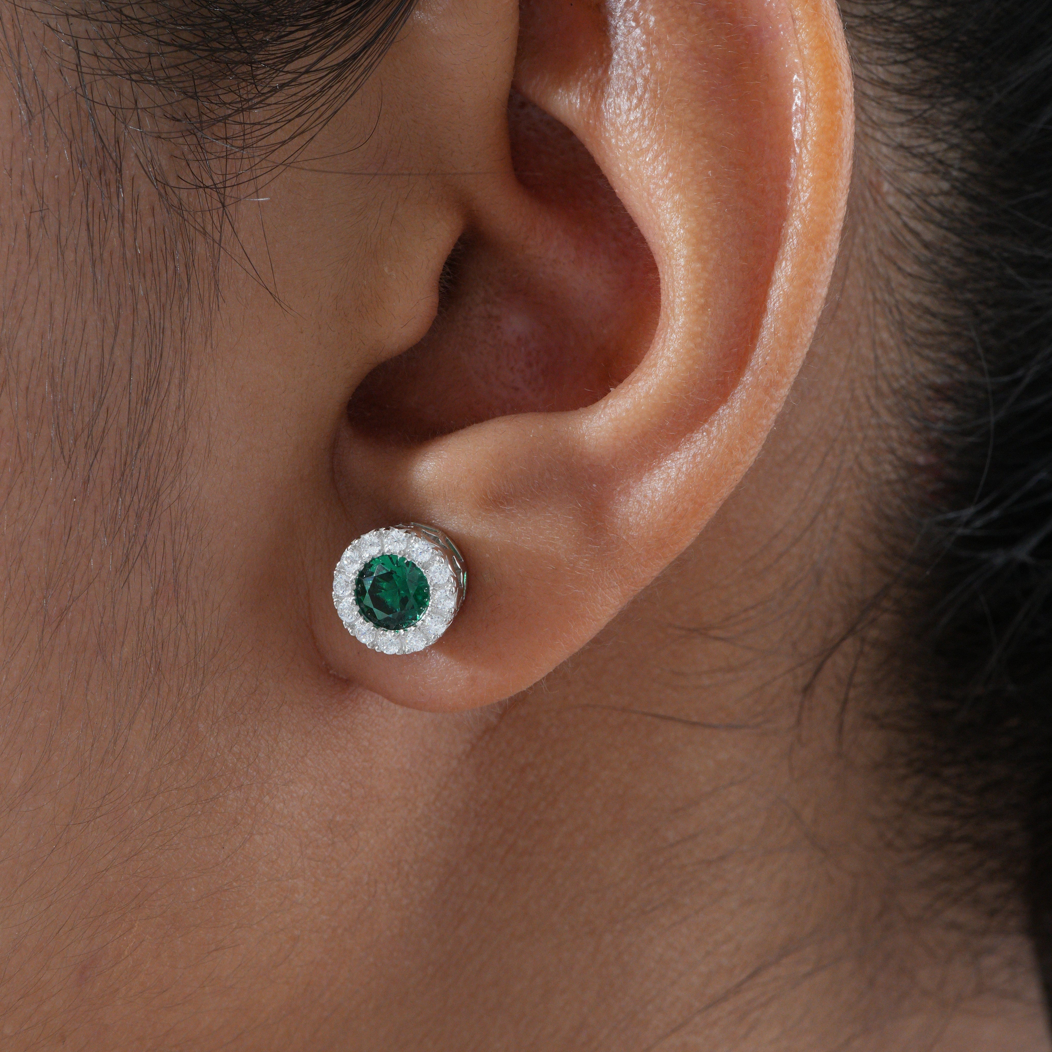 Close-up of an ear wearing a green gemstone earring.