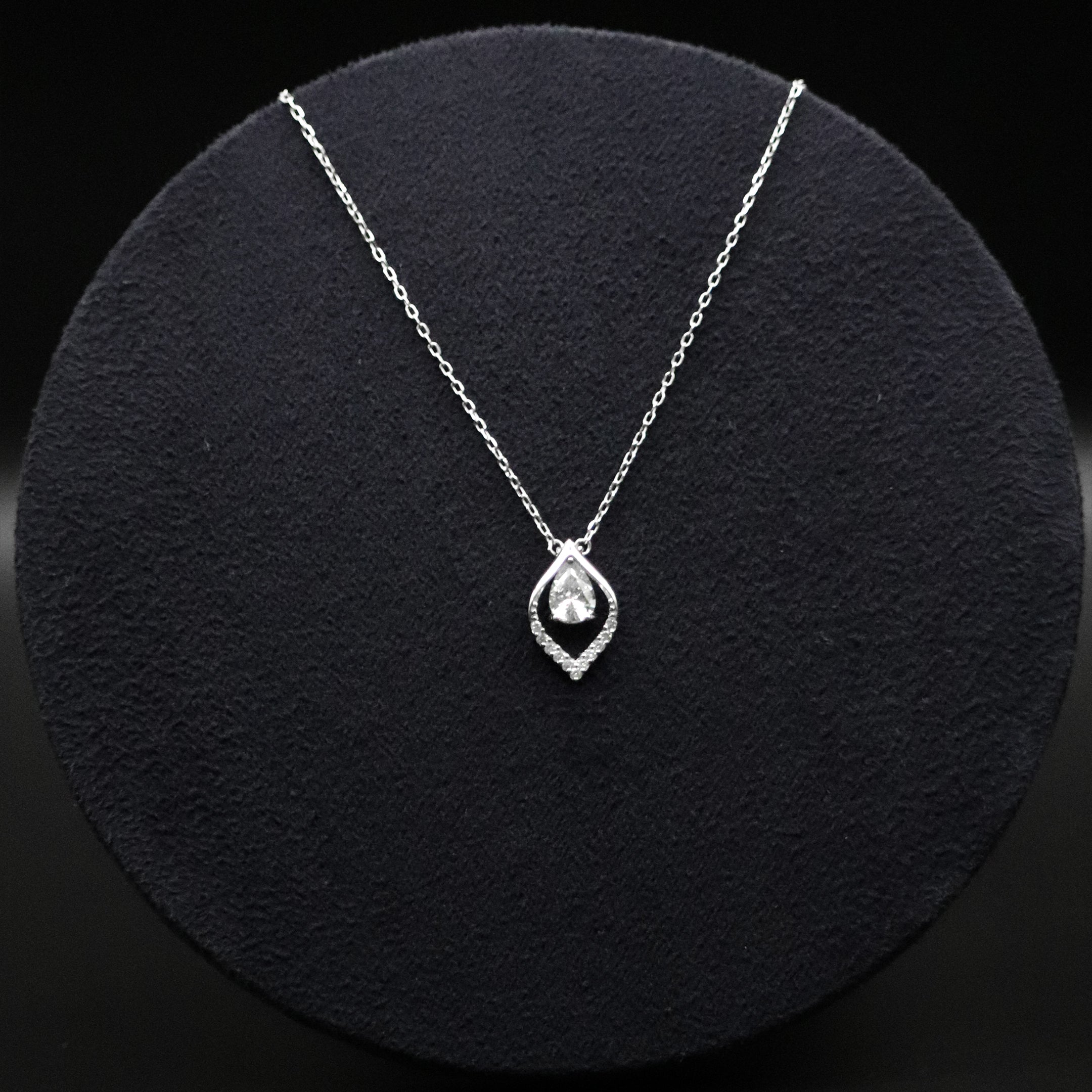 Silver necklace with a teardrop-shaped pendant on a black textured surface