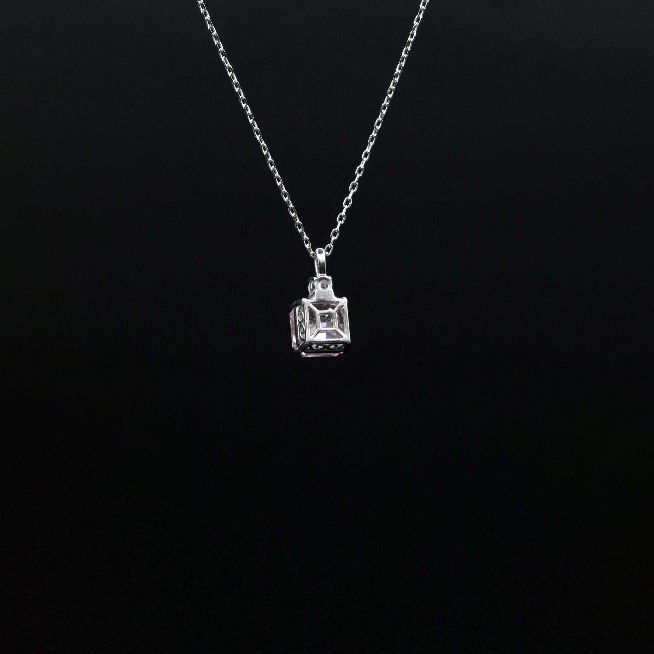 Silver necklace with a square pendant on a black background