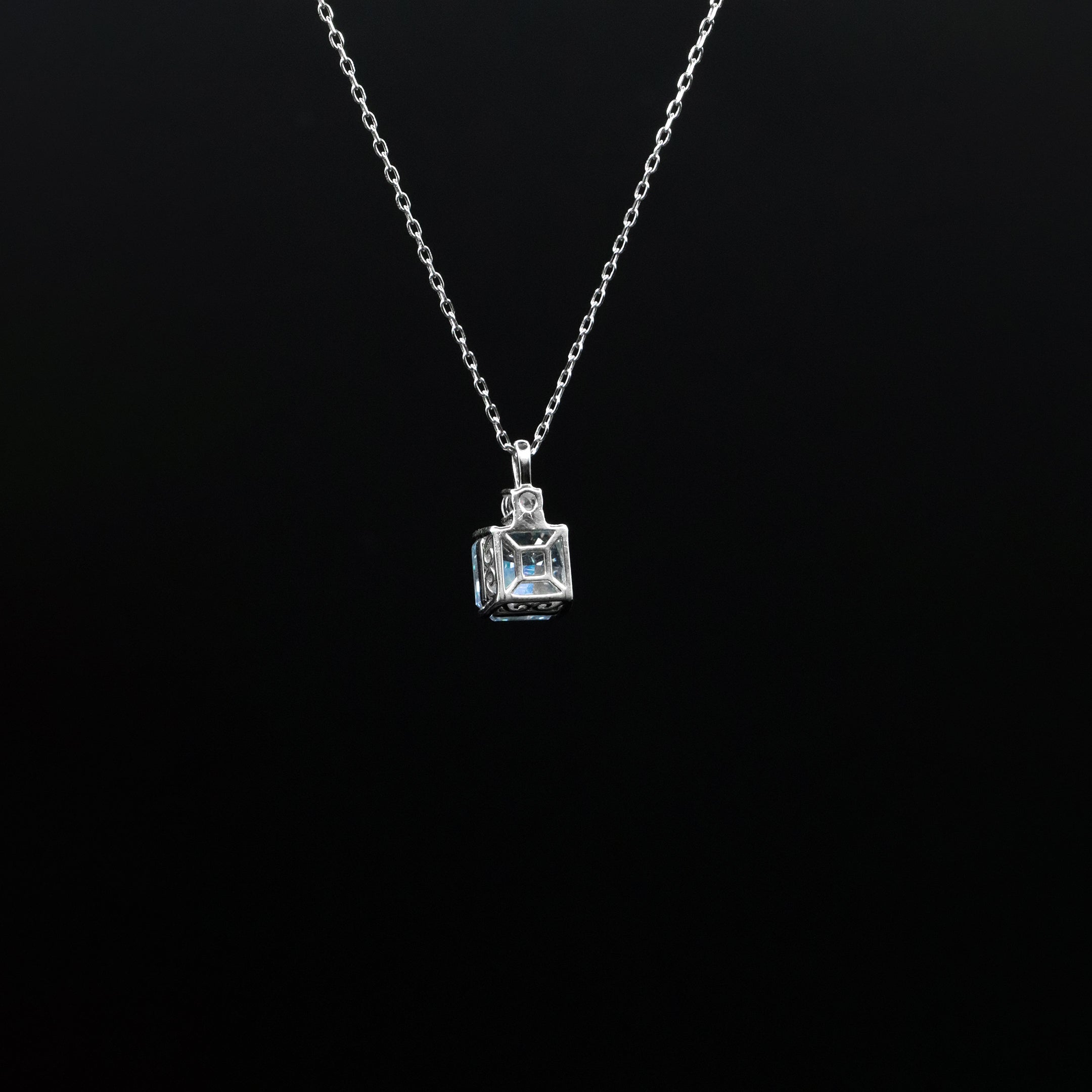 Silver necklace with a square pendant on a black background
