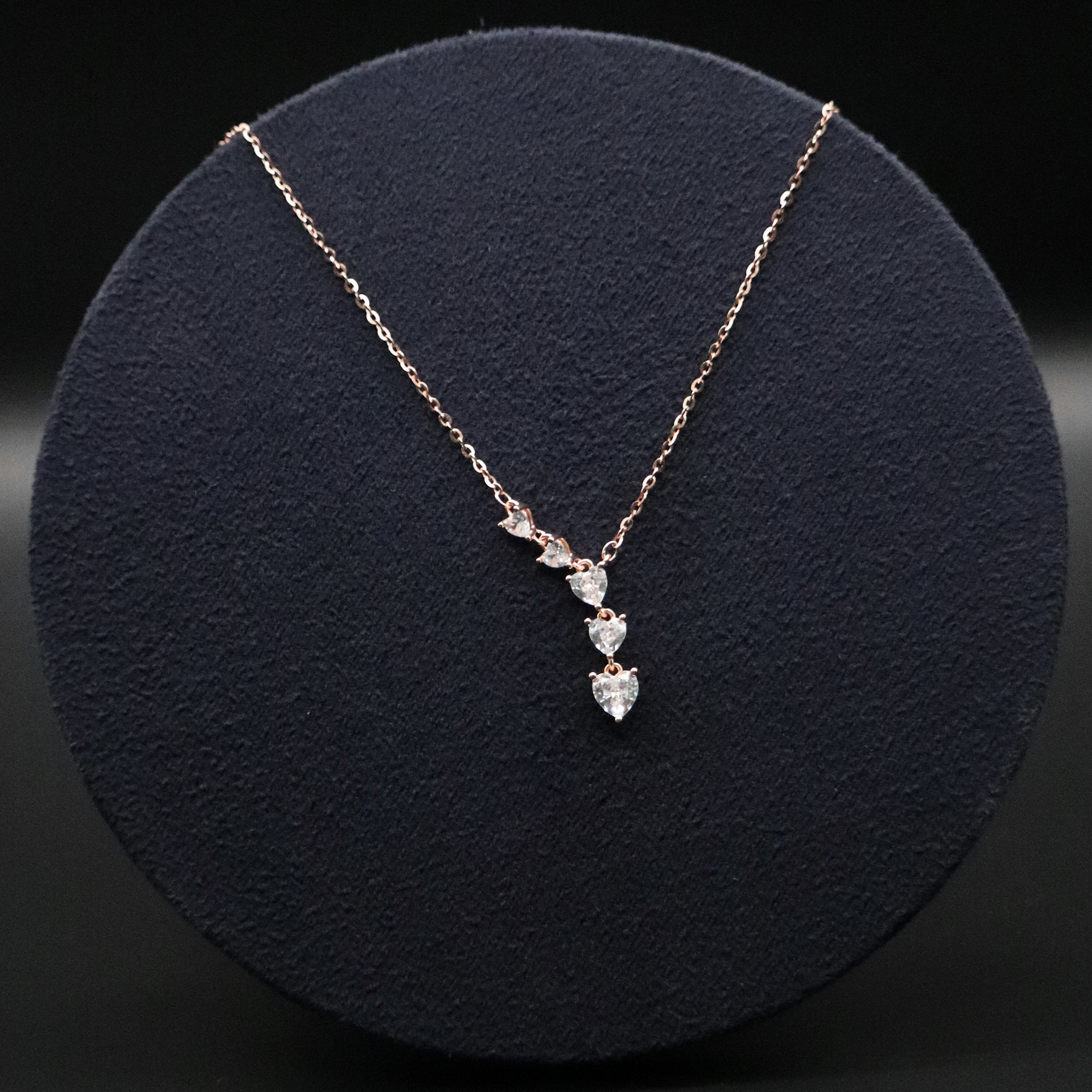 Rose gold necklace with heart-shaped pendant on a dark background