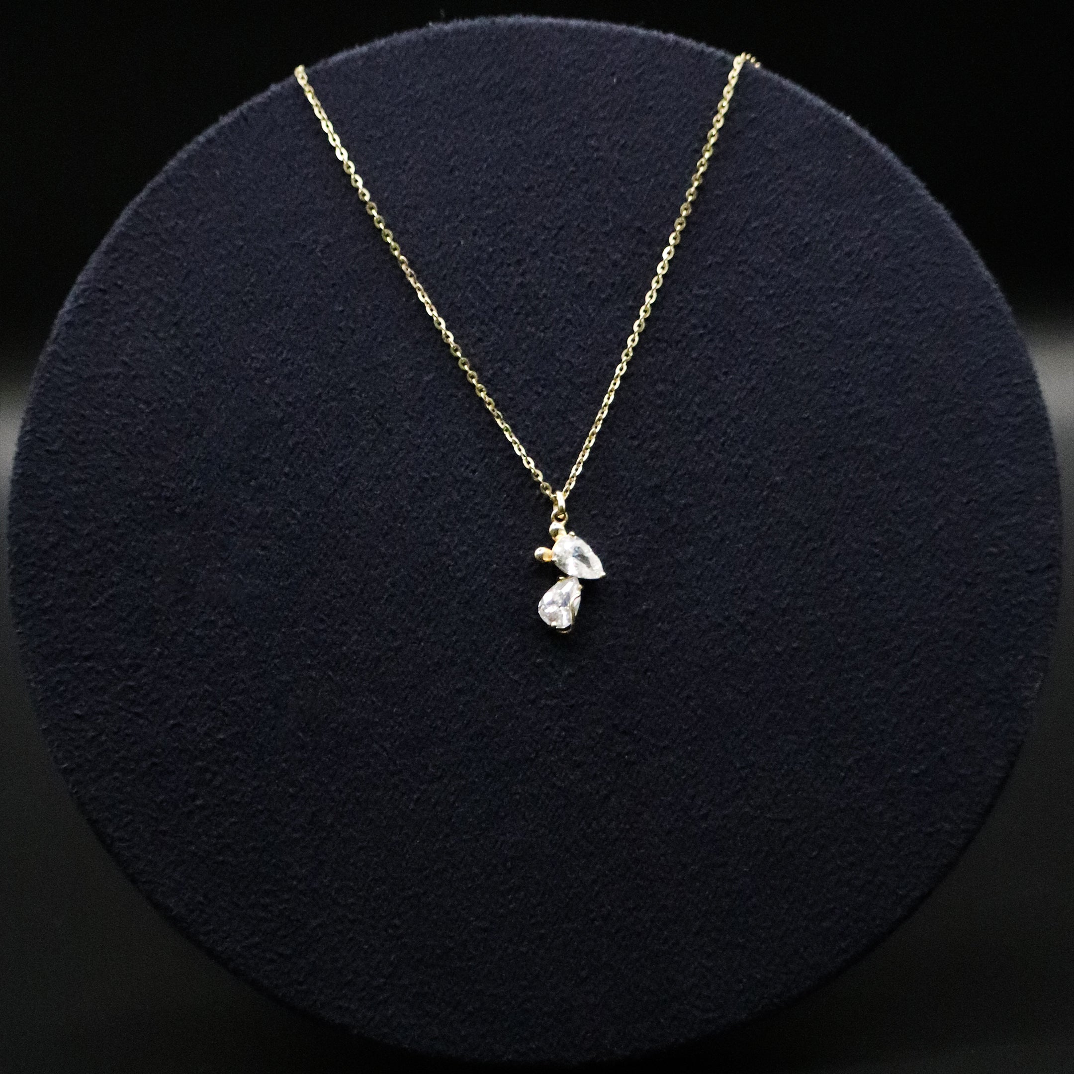 Gold necklace with a pendant on a black round cushion