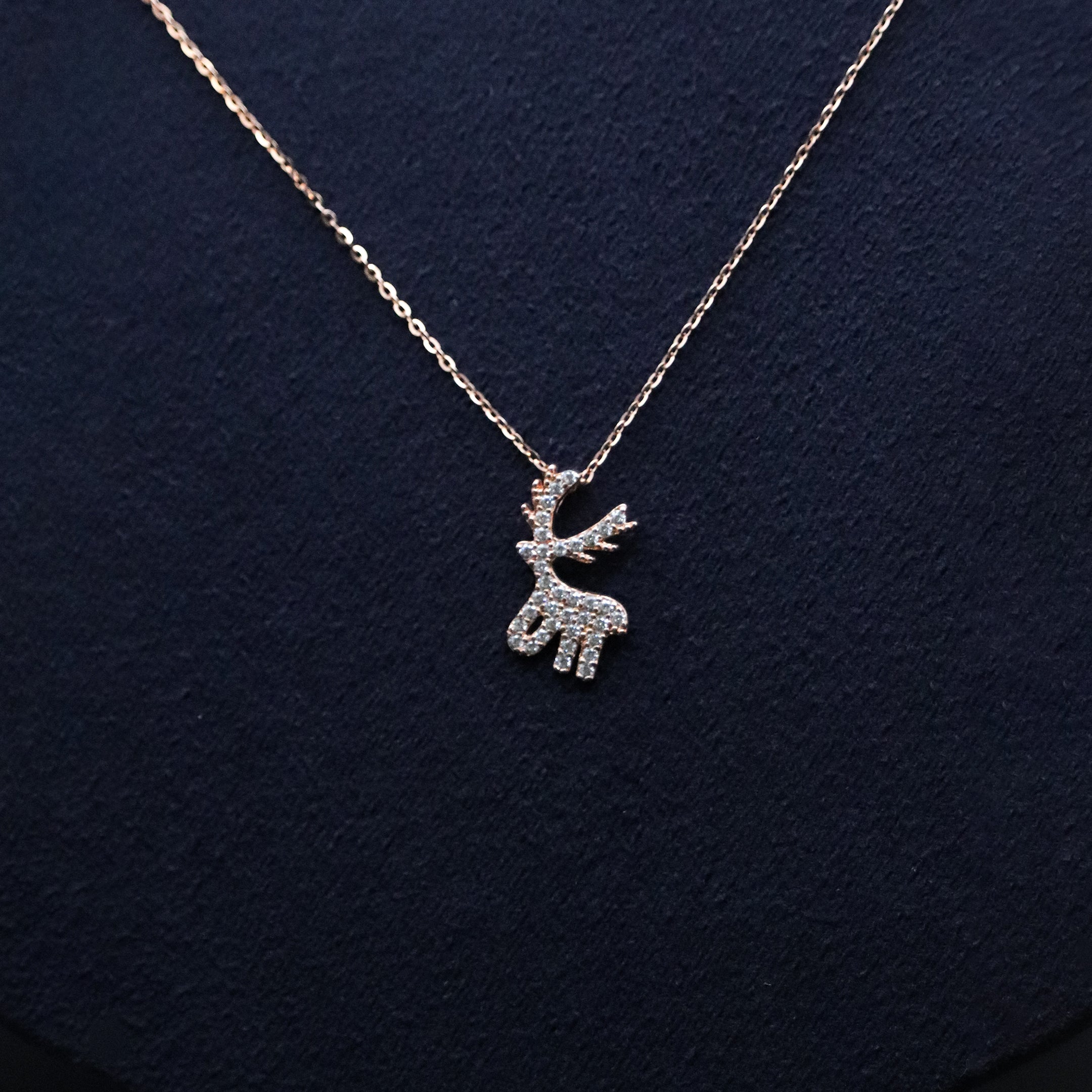 Silver reindeer pendant necklace on a dark blue background