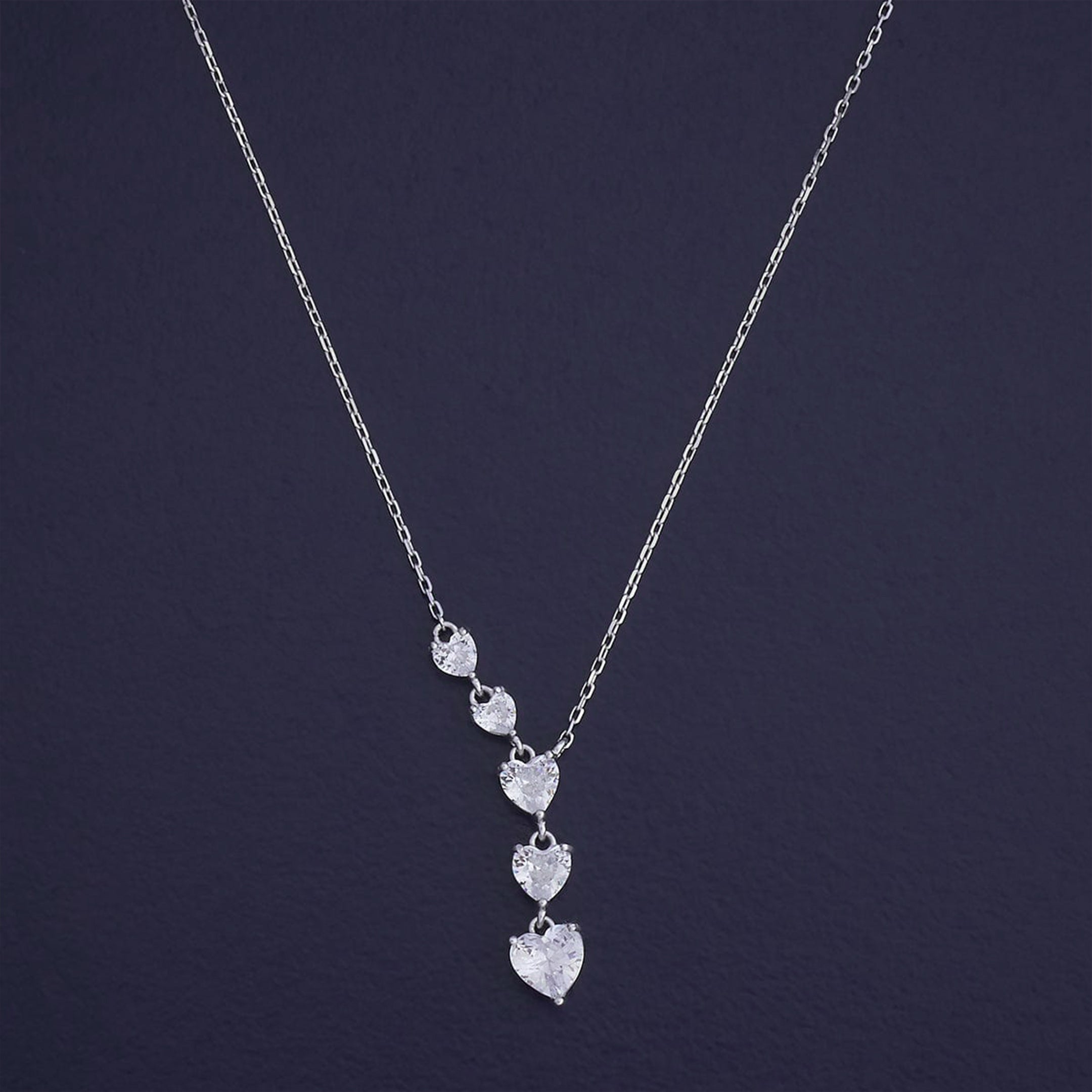 Silver necklace with heart-shaped pendants on a dark background