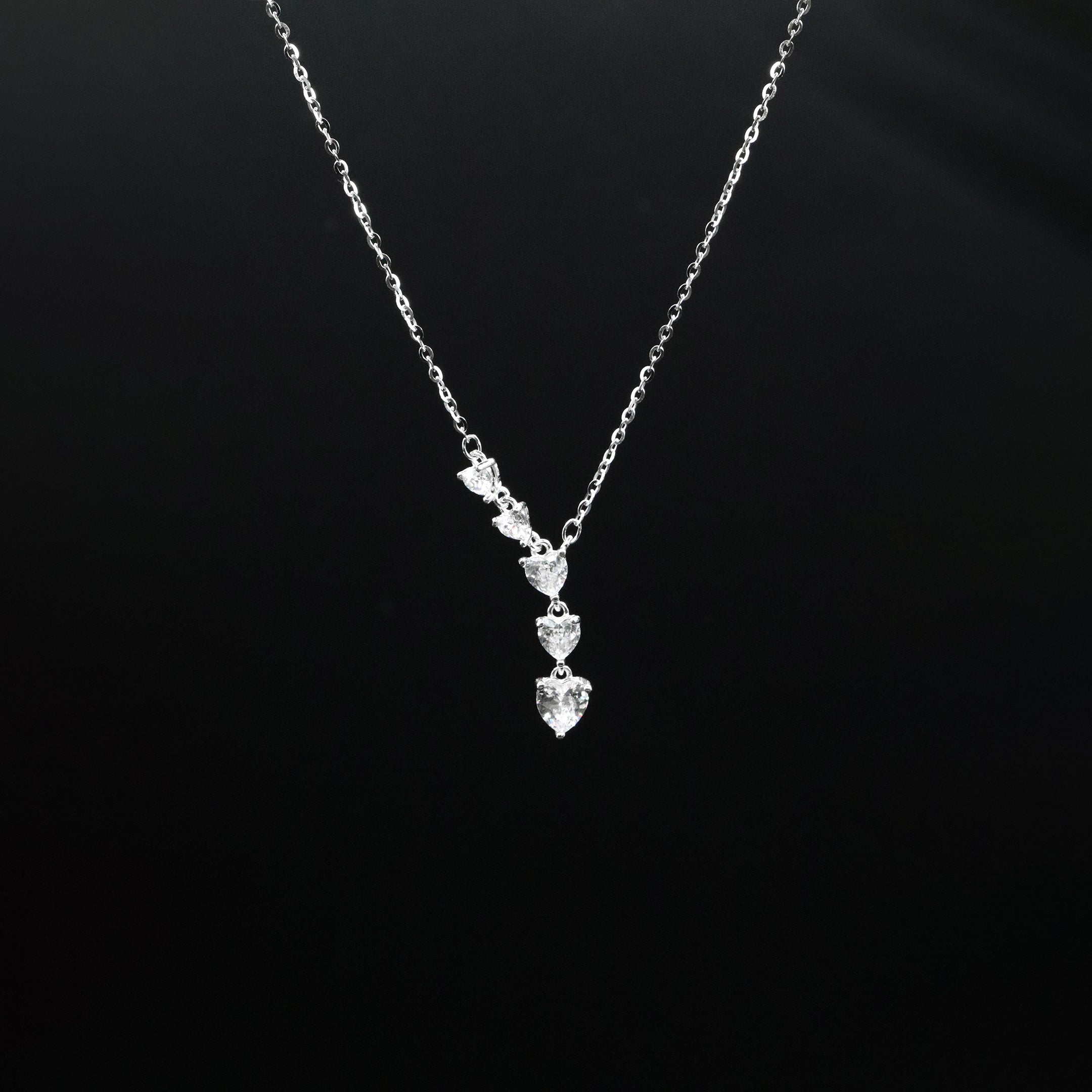 Silver necklace with a heart-shaped pendant on a black background