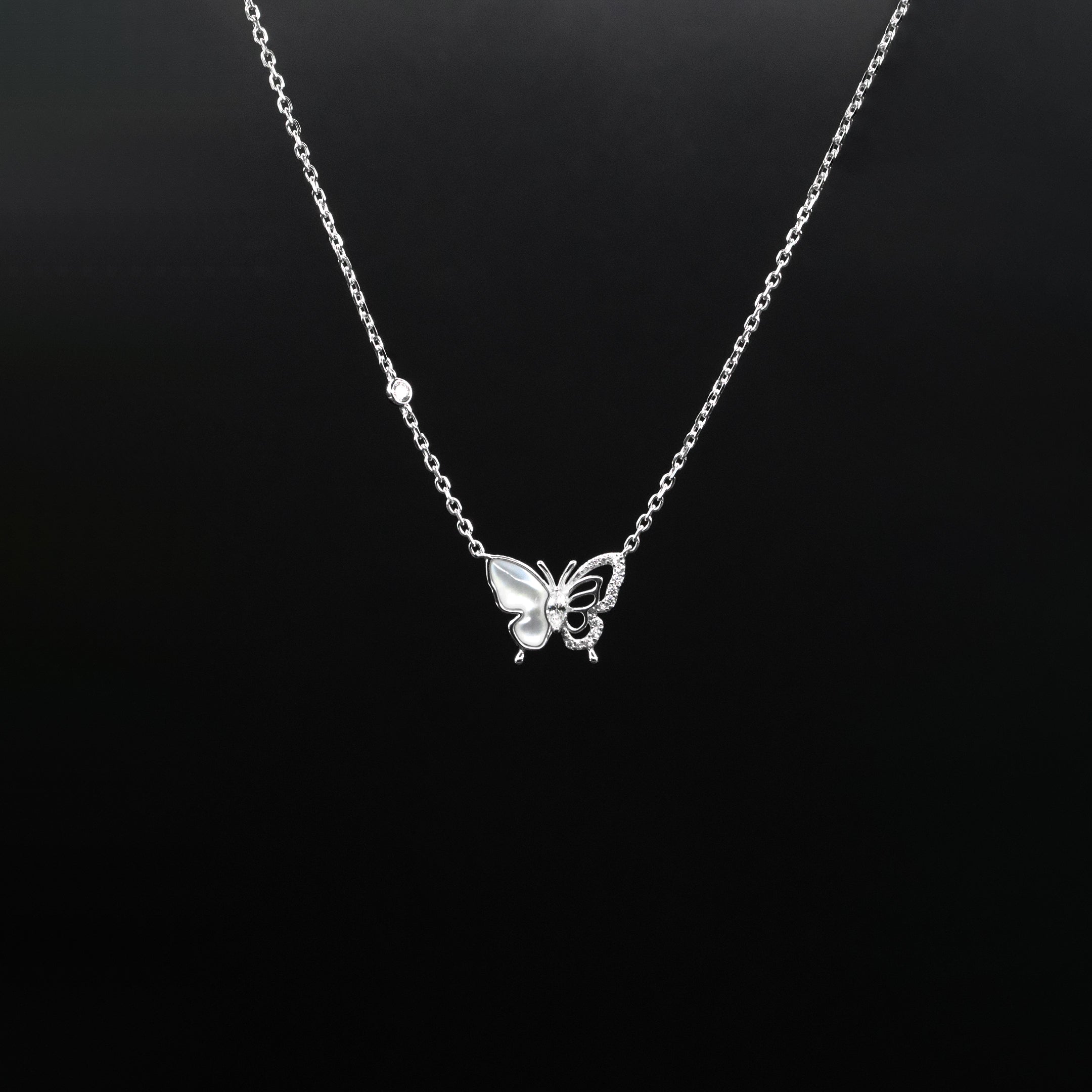 Silver butterfly necklace on a black background