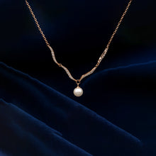 Gold necklace with a pearl pendant on a dark blue fabric background