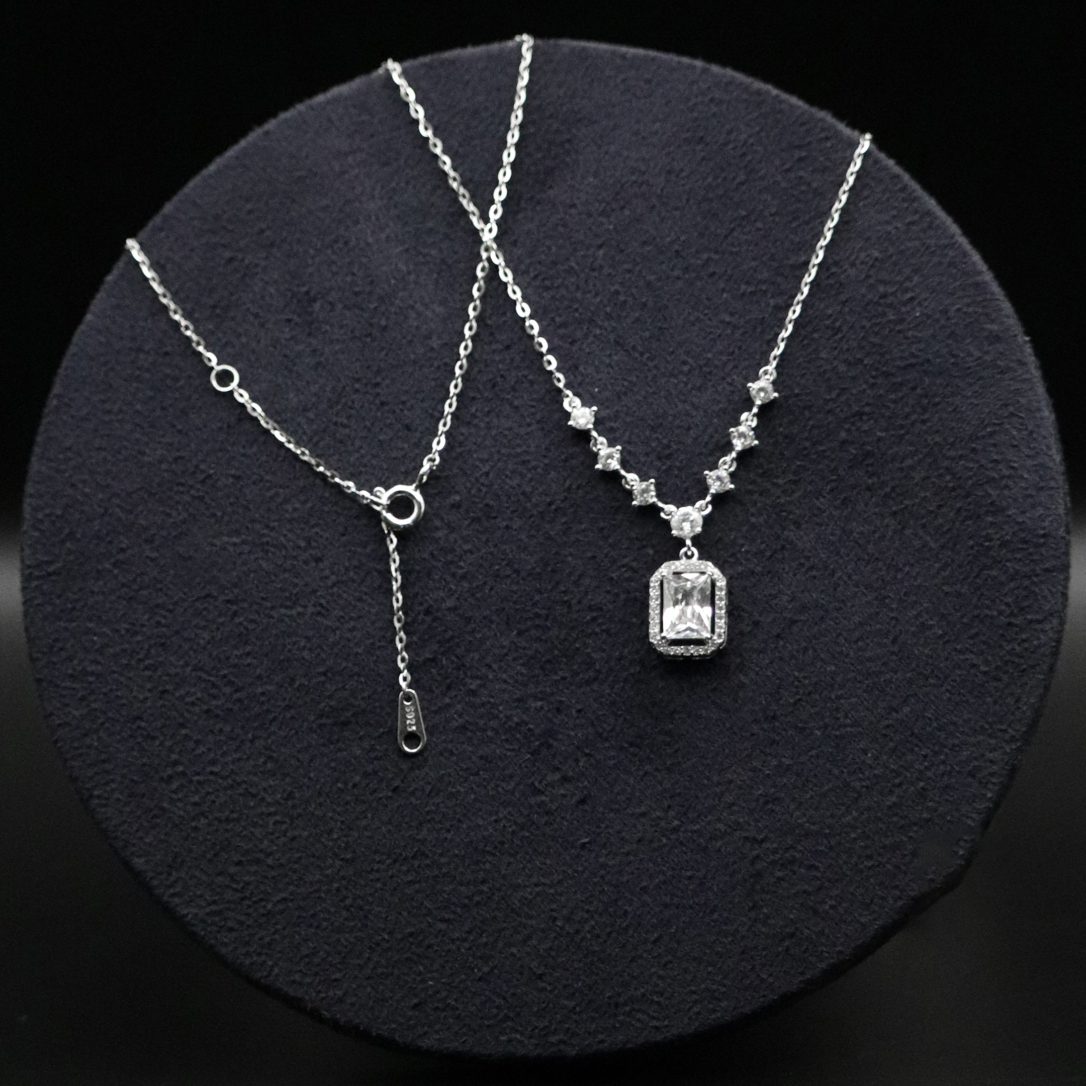Silver necklace with a pendant on a dark circular stand