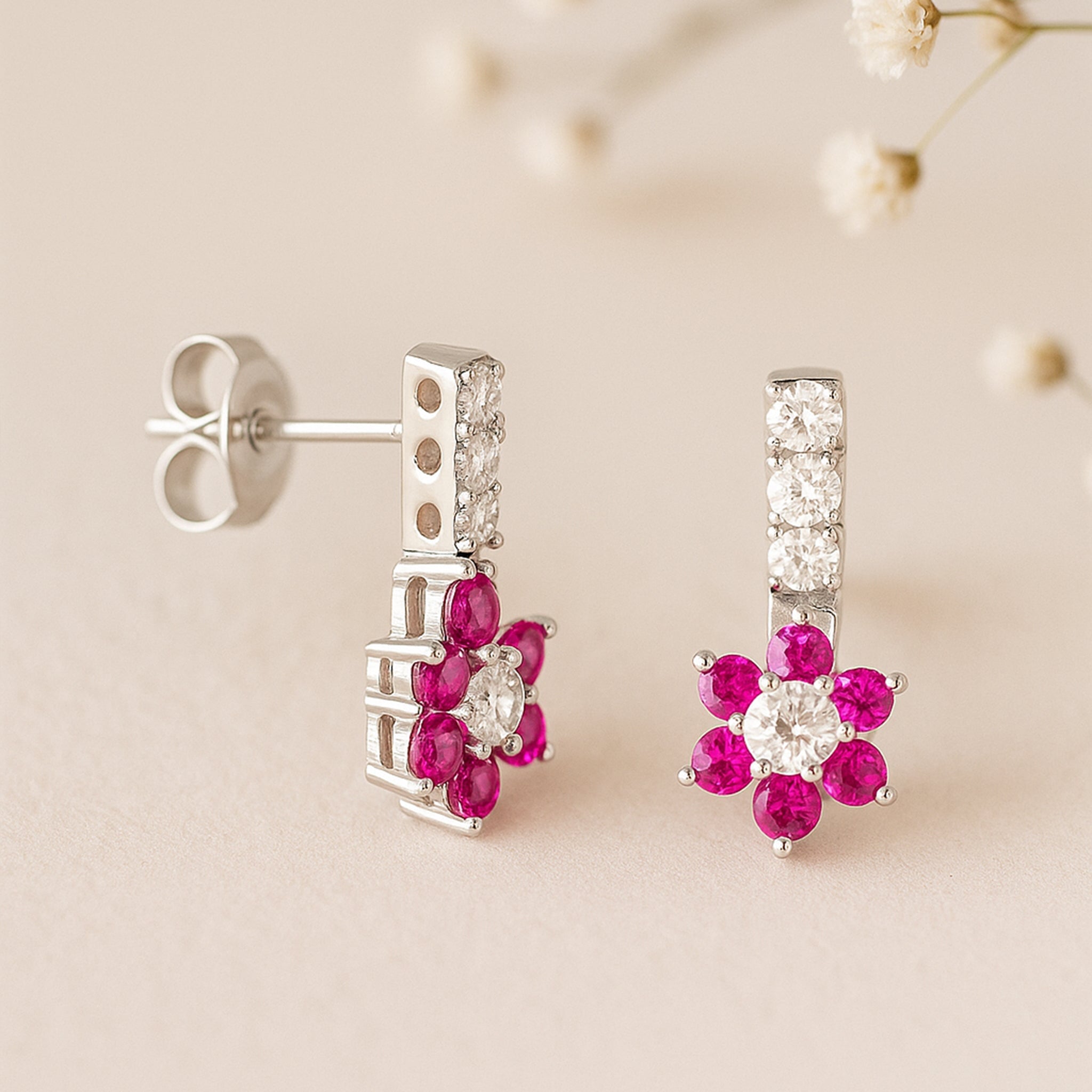 Pair of earrings with pink gemstones on a beige background