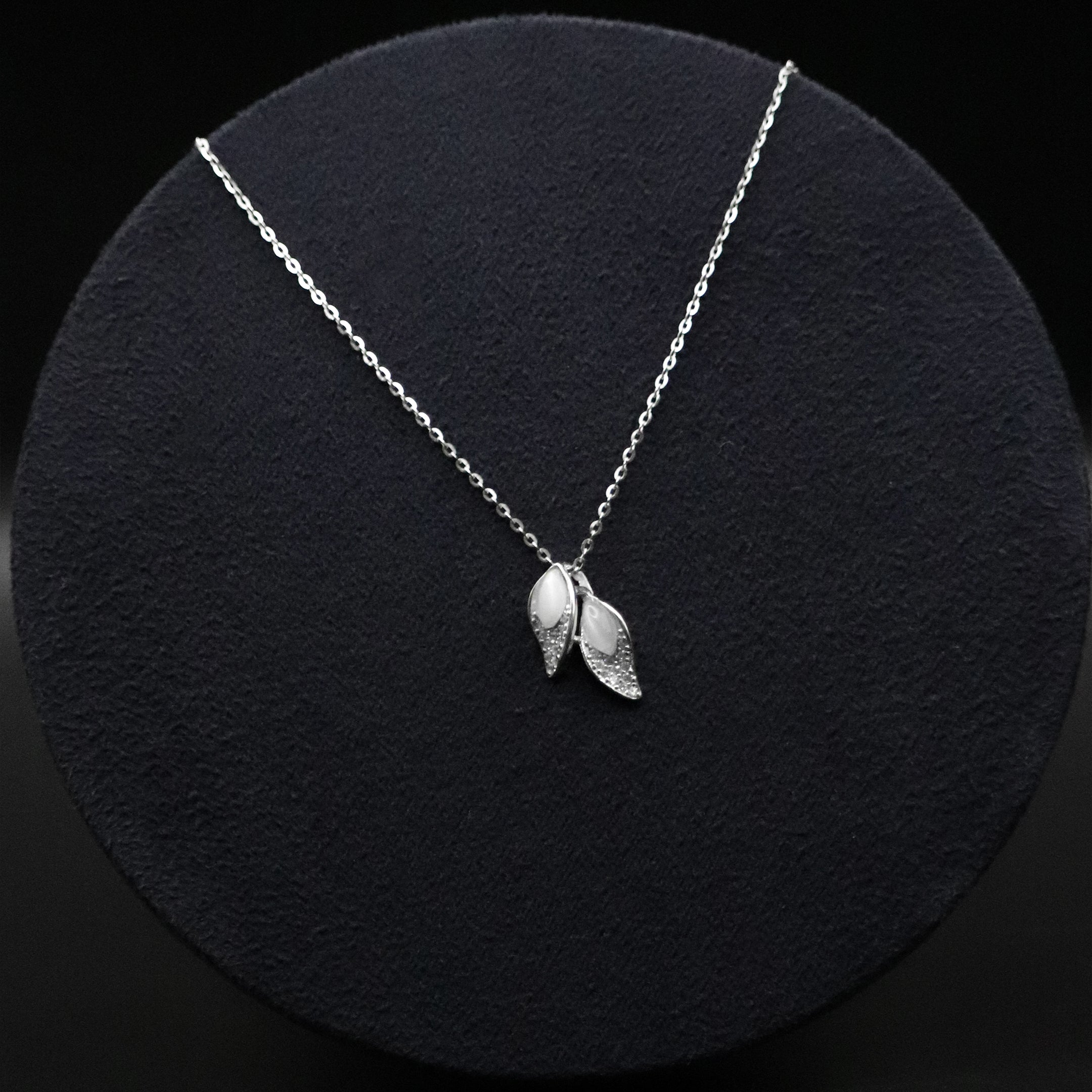 Silver necklace with leaf pendants on a black background