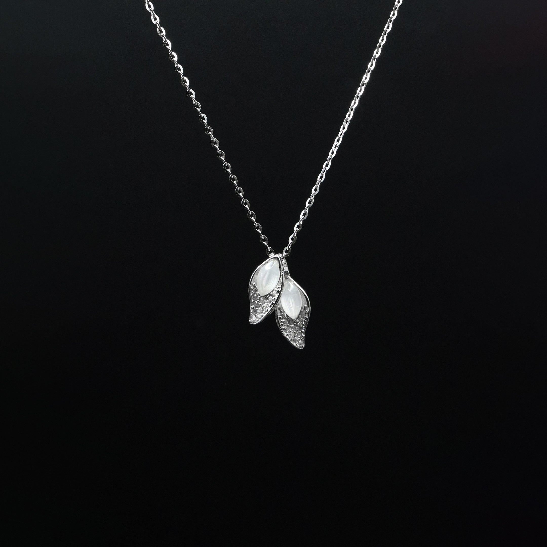 Silver necklace with leaf-shaped pendant on a black background