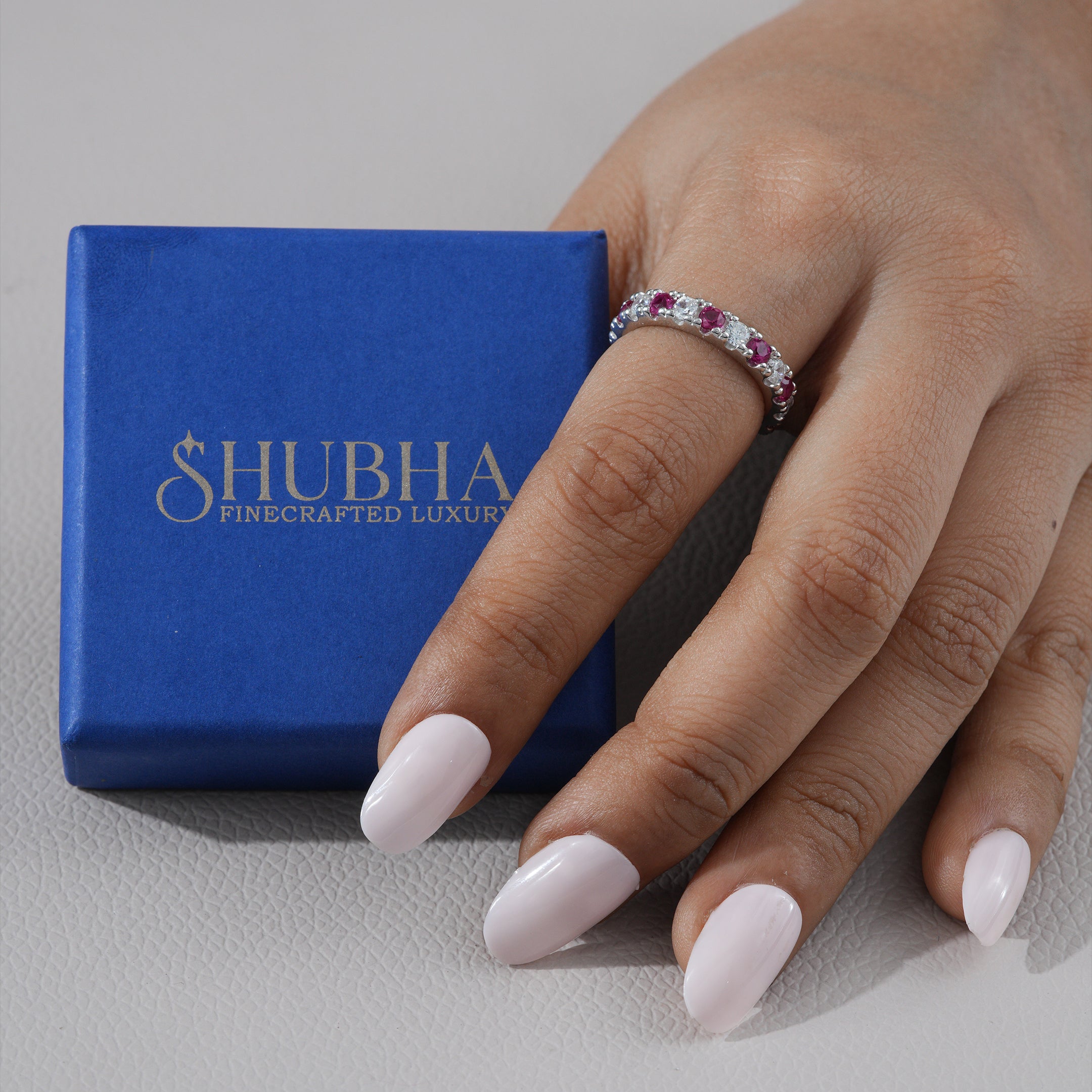 Hand wearing a ring with a blue Shubha box in the background
