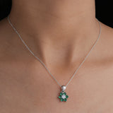 Silver necklace with a green gemstone pendant on a person's neck against a black background