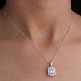 Silver necklace with a diamond pendant on a person's neck against a neutral background